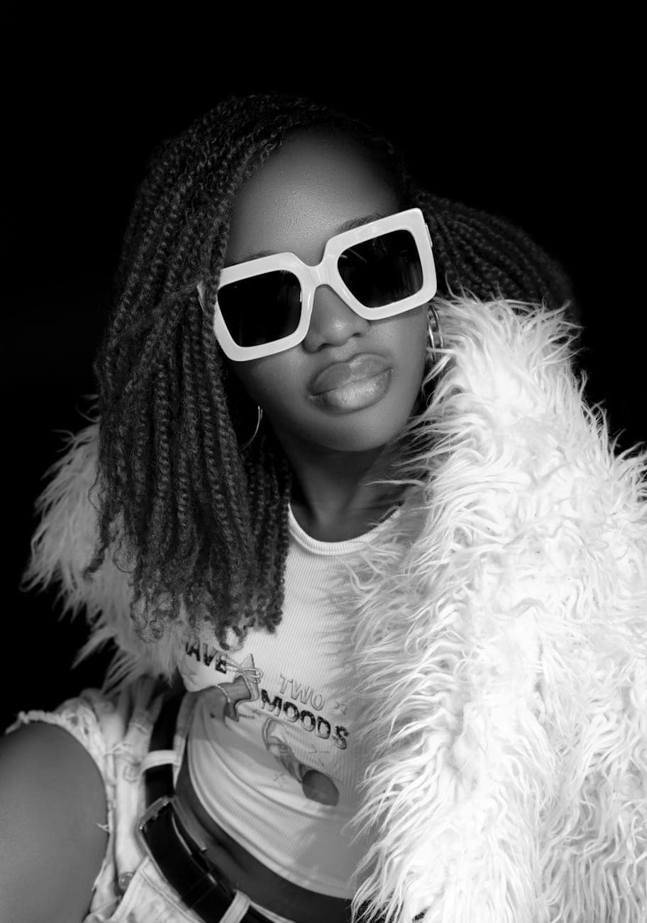 Monochrome portrait of a stylish woman with sunglasses and a fluffy jacket.