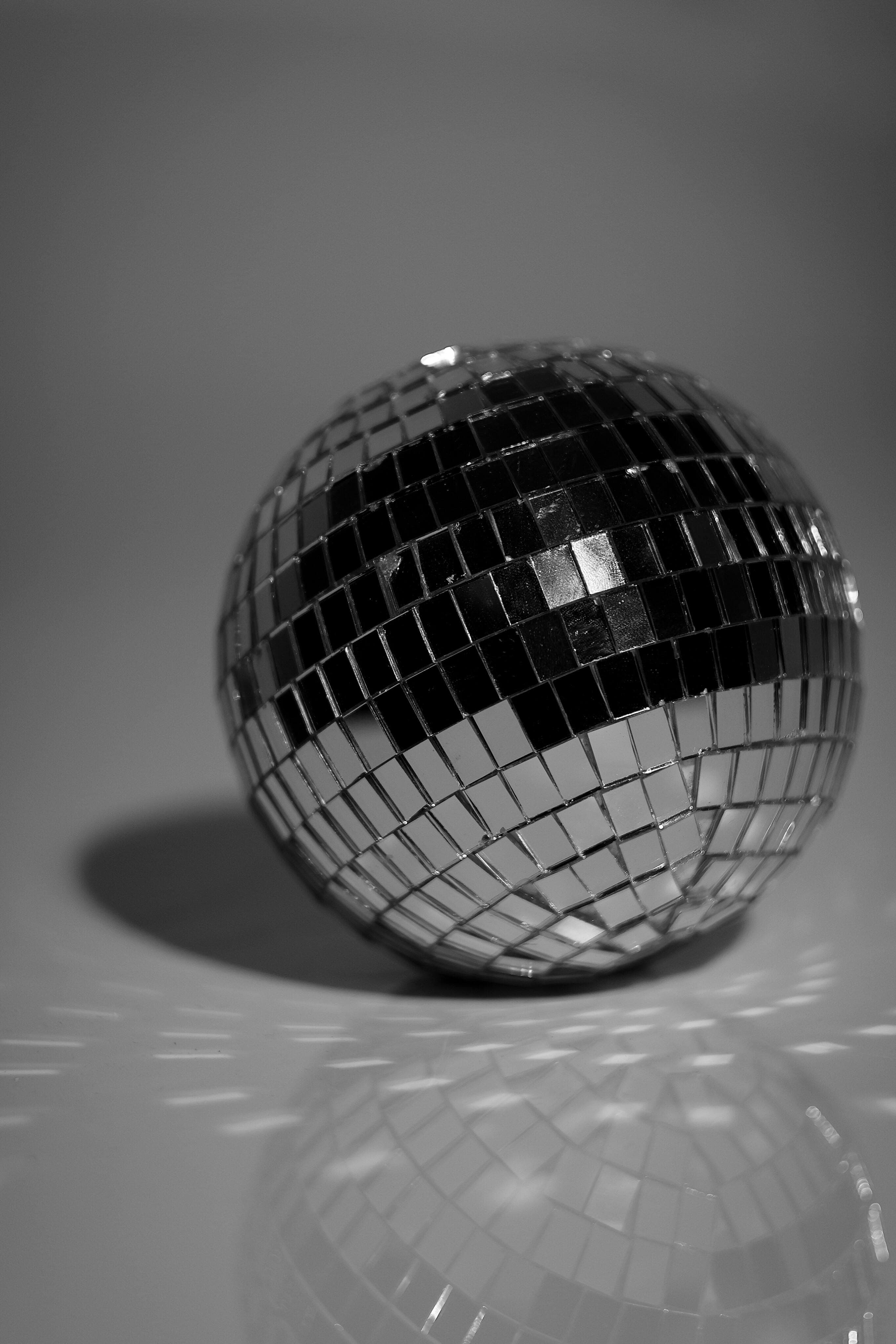 Elegant close-up of a reflective disco ball in black and white, casting shadows.