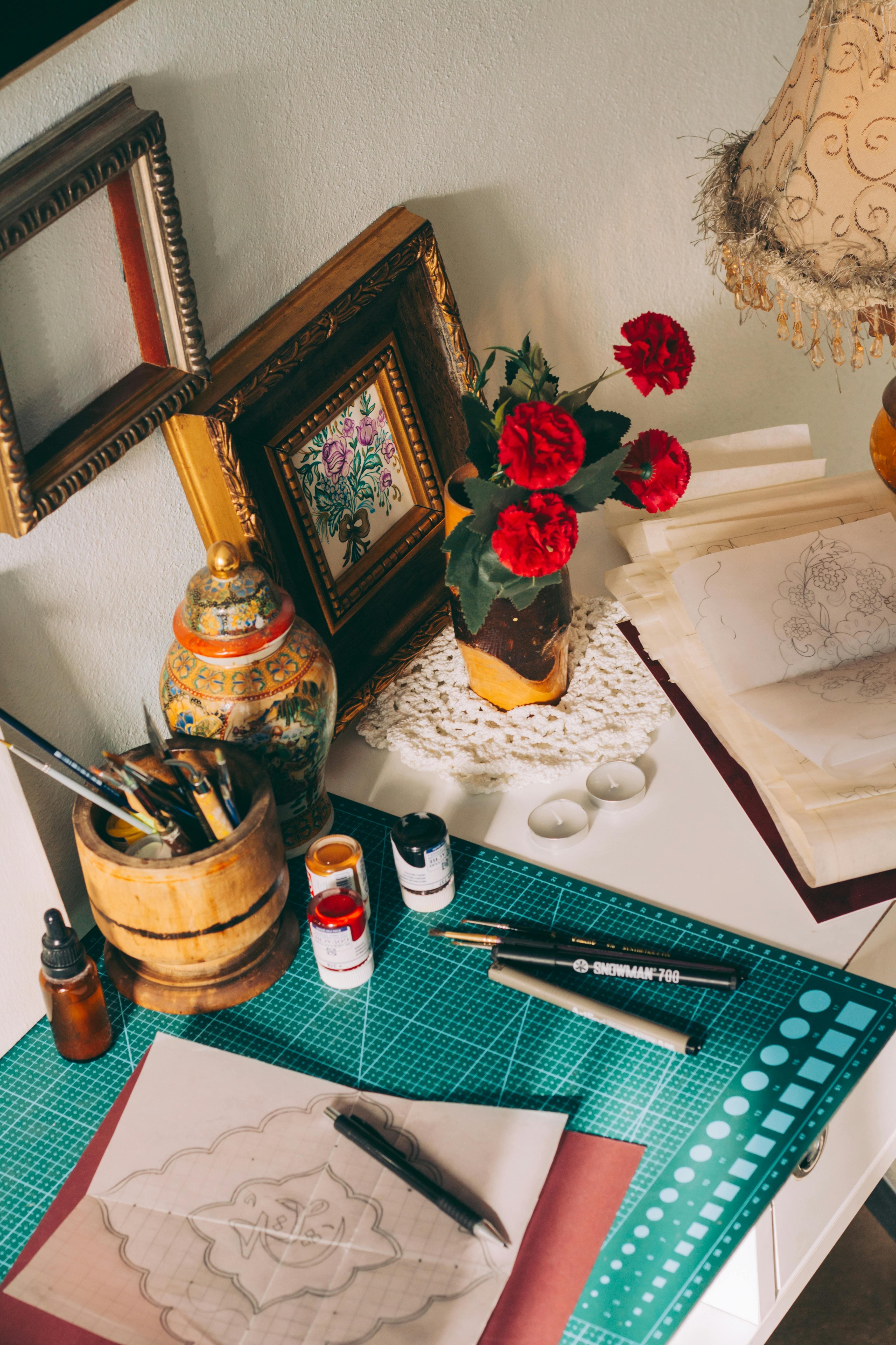 Warm-toned art studio with supplies and red flowers, inspiring creativity.