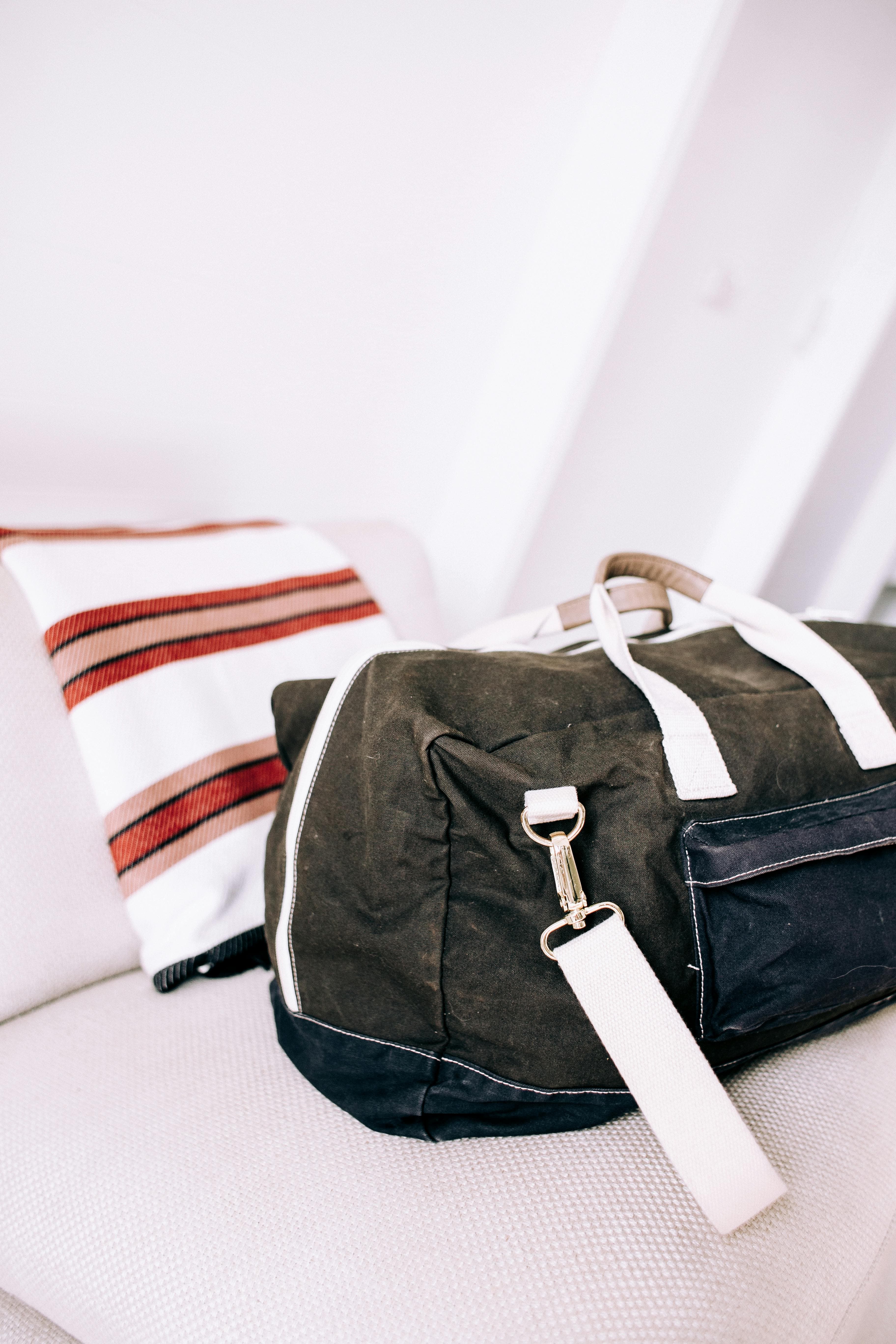 A chic travel bag resting on a modern sofa with a stylish throw blanket.