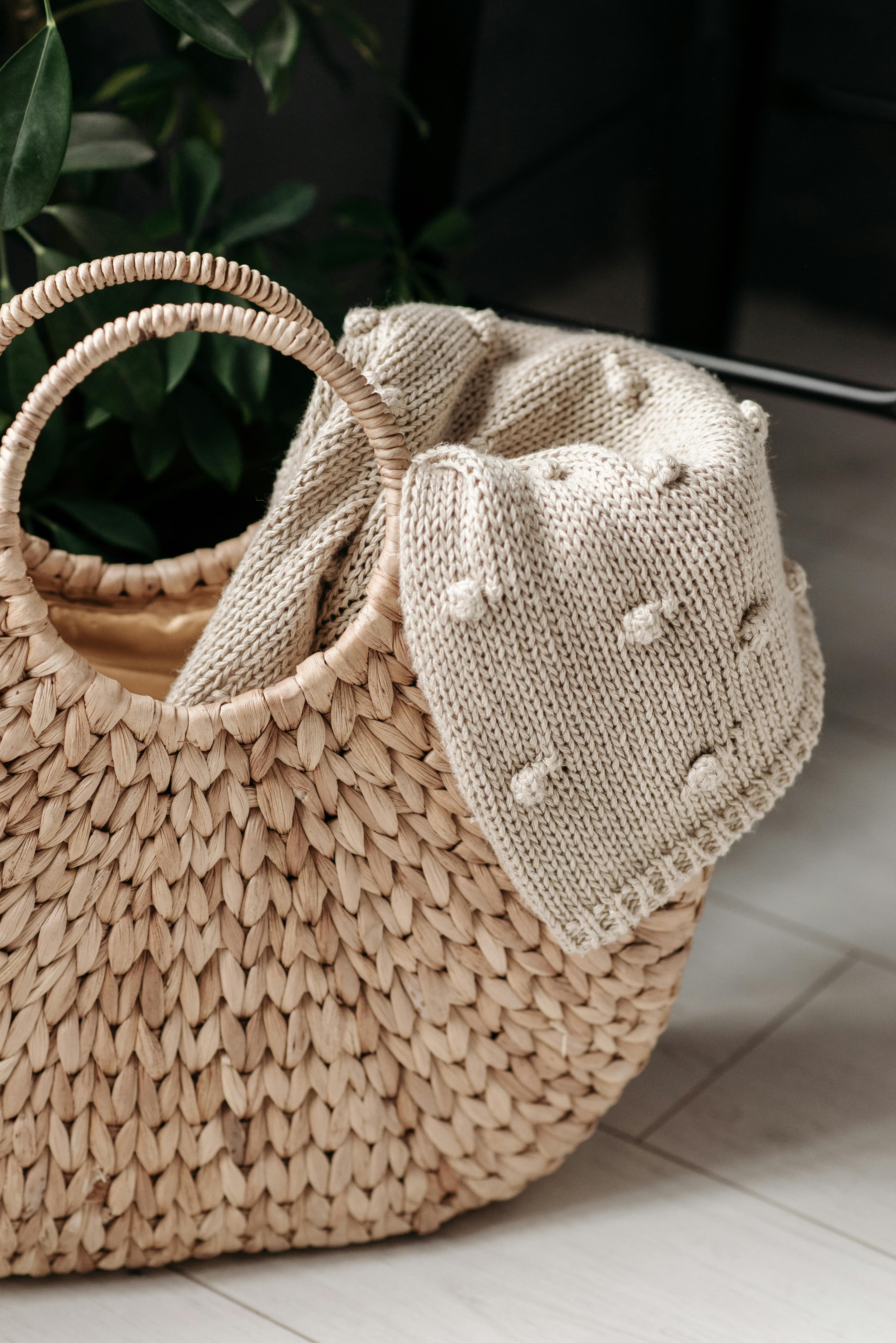 A detailed close-up of a handwoven basket with a textured knit blanket indoors.