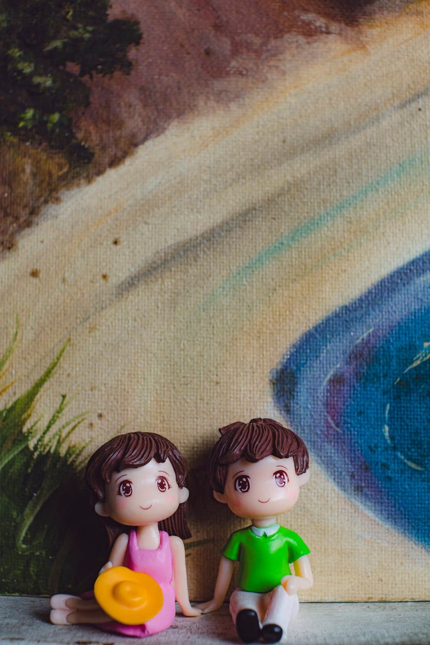 Plastic figures of romantic couple with hat holding hands against painting of sandy coast and ocean