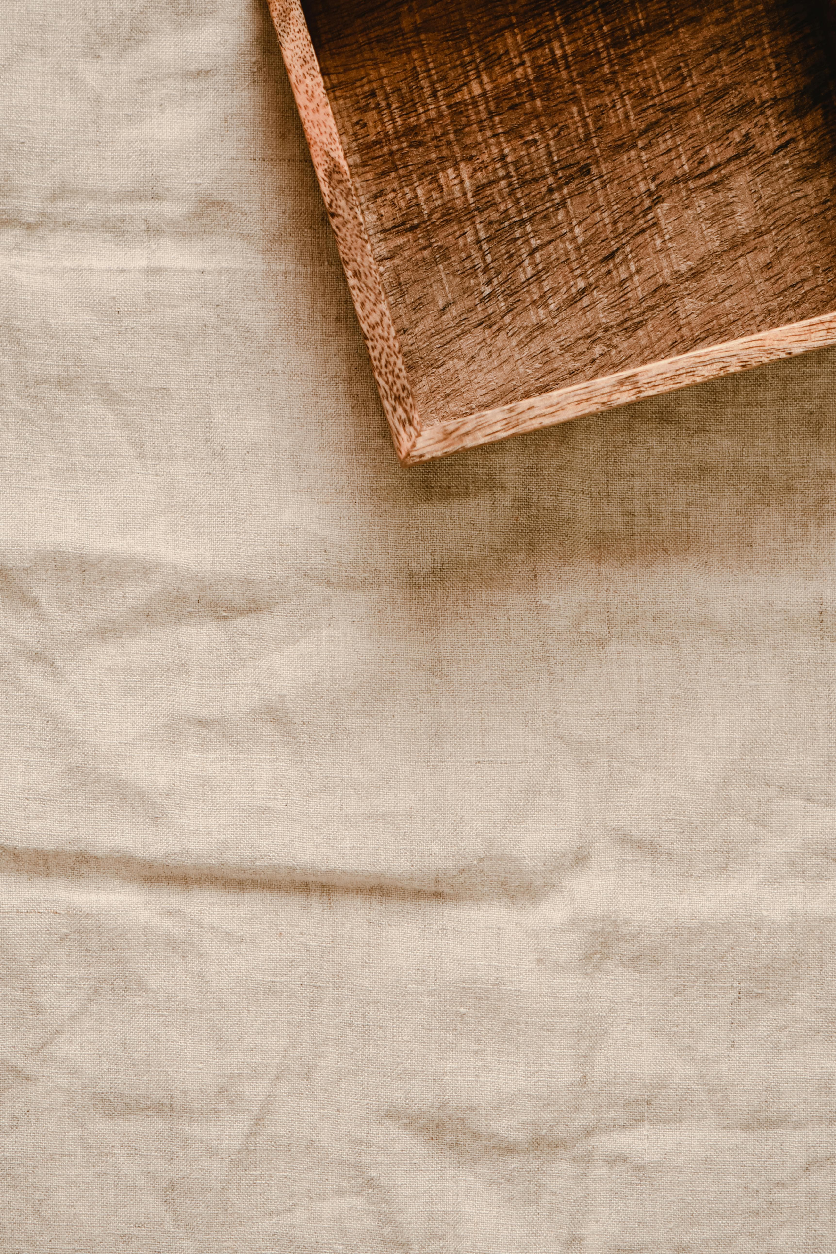 Close-up view of a rustic wooden box positioned on creased linen fabric, offering natural texture and copy space.