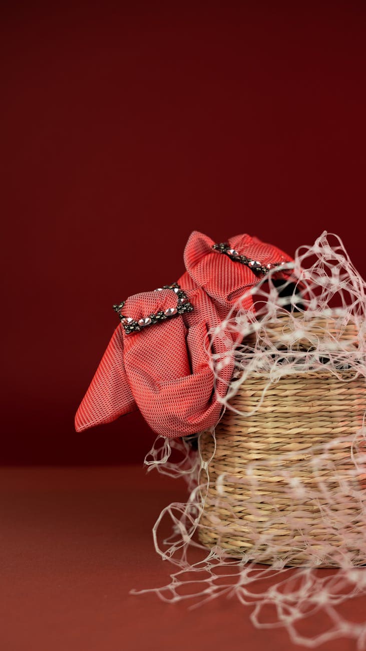 A woven basket adorned with intricate red fabric and ribbons against a vibrant red backdrop.